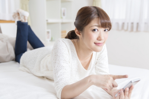 部屋の中で寝ころびながらスマホを使ってネットショッピングを楽しむ女性03
